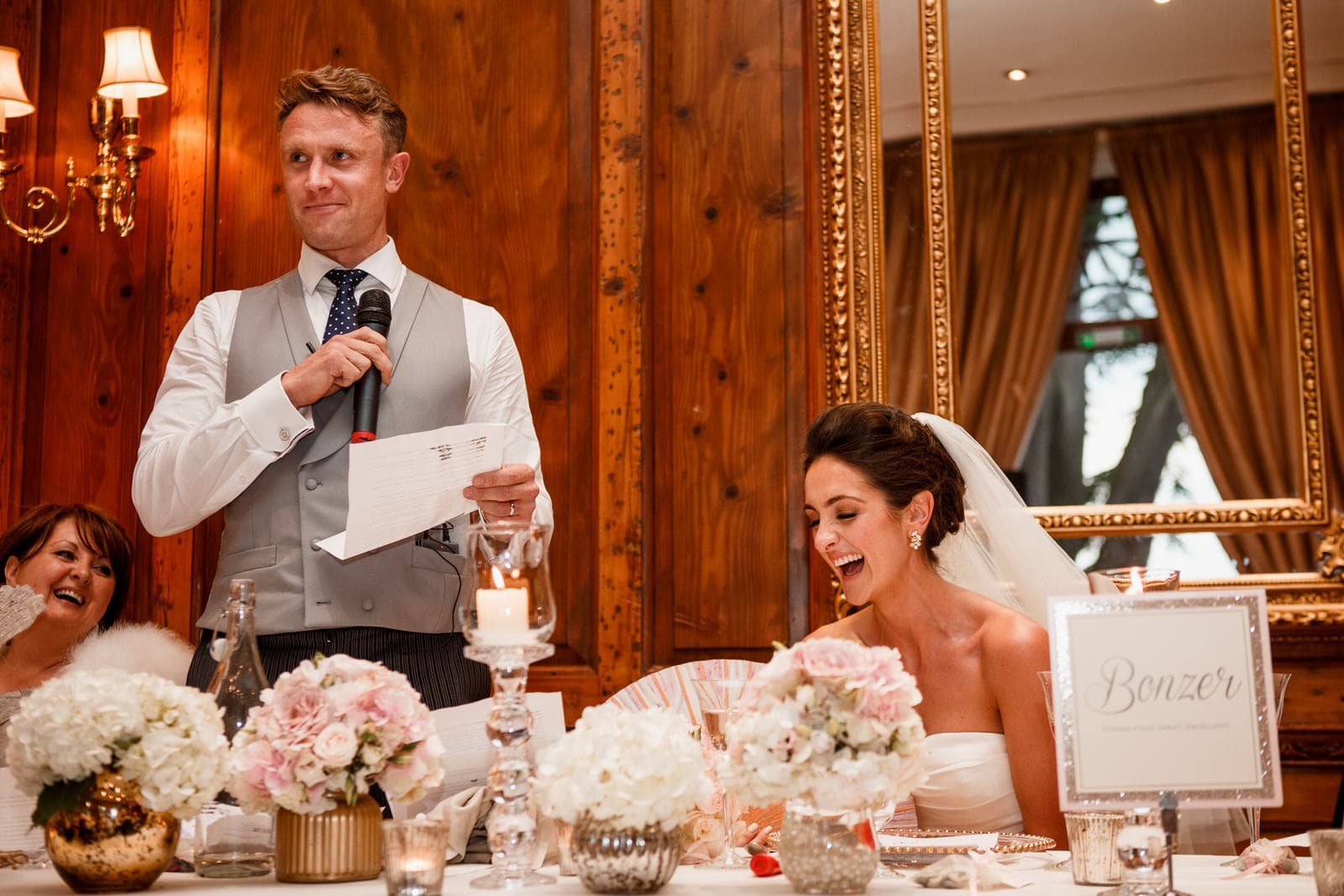groom giving speech and bride laughing