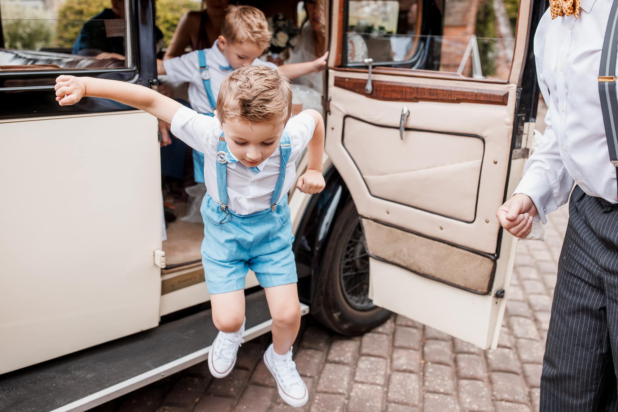 page boy jumping out of wedding car